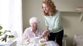 Woman feeding mother at table