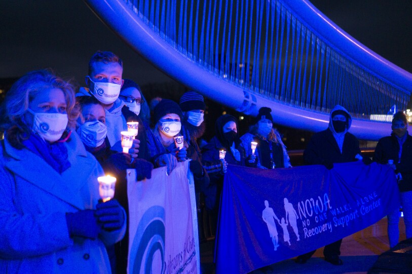 A group of people hold candles and a sign to raise awareness about sexual exploitation and human trafficking.