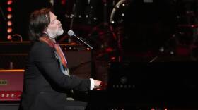 Rufus Wainwright sings as he plays piano on stage.