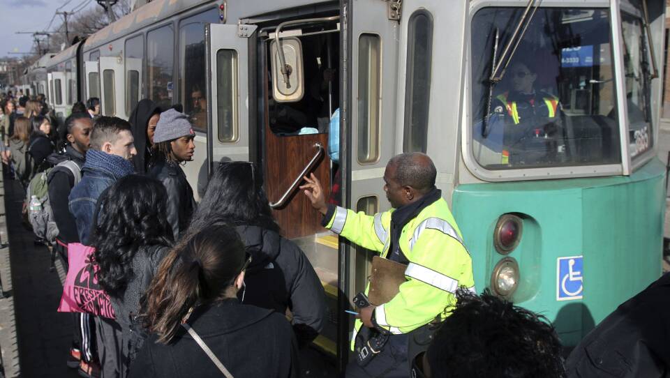 A conductor directs people onto the Green Line.
