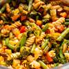 Bowl of rotini, cut string beans, chunks of carrots, cannellini beans, and kale in a tomato soup base