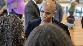 A Black woman listens intently to two other women seen from the back of their heads.