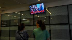 Two women look up at TV news