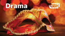 A red drama mask on a flat surface with an orange lit background and the words "Drama GBH" written above the mask.
