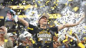 A woman in an "Iowa Champions" T-shirt bathes in confetti falling from the air inside a stadium.
