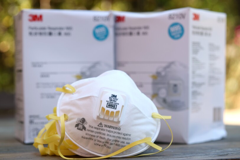 An N95 mask sits on a table in front of two boxes.