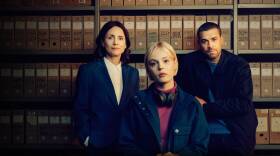 Woman and man standing in front of shelves of file boxes on and a woman with short blond hair sitting in front of them