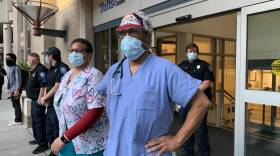 Emergency Room physician Dr. Furman Walls stands outside the Tufts Medical emergency room doors, watching a parade march by on May 31, 2020