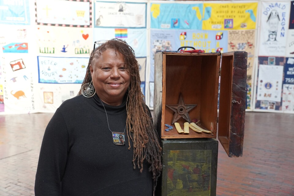 A woman stands next to an art installation, which is an open box, containing a copper star.